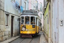 Iconic yellow Tram 28 on narrow Alfama street